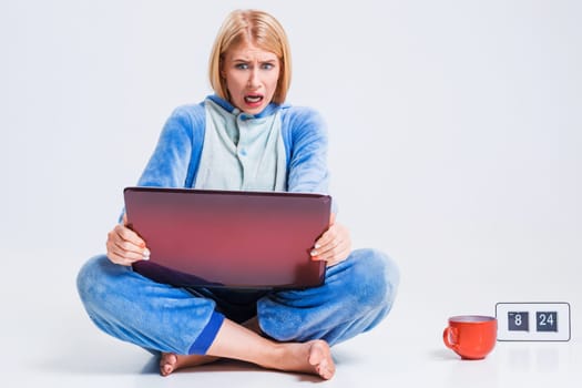 girl in pajamas with a laptop lying on the floor. studying or doing online shopping. work from home. Surprised and crazy