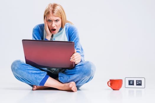 girl in pajamas with a laptop lying on the floor. studying or doing online shopping. work from home. Surprised and crazy