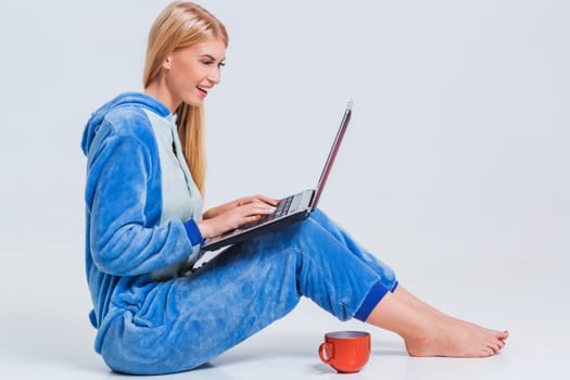 girl in pajamas with a laptop lying on the floor. studying or doing online shopping. work from home. Satisfied and smiling