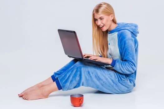 girl in pajamas with a laptop lying on the floor. studying or doing online shopping. work from home. Satisfied and smiling