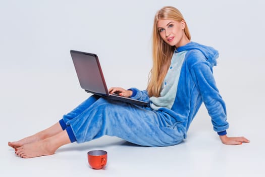 girl in pajamas with a laptop lying on the floor. studying or doing online shopping. work from home. Satisfied and smiling