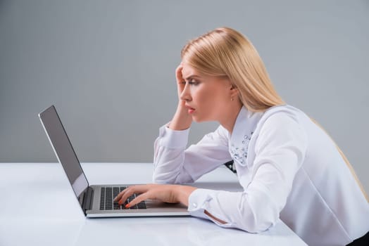 Young businesswoman working at laptop computer. tired, hunched, pleased