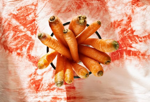 Bunch of orange carrots in bowl on colored table ,