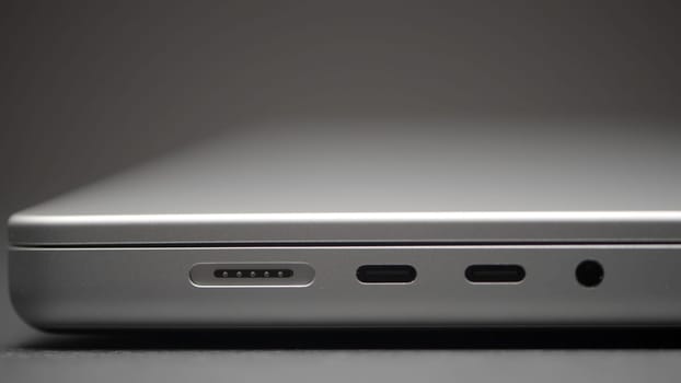 Extreme close up of a laptop isolated on a greu wall background. Action. Closed portable computer lying on the table