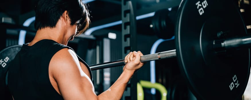 A muscular man with bicep veins holding a barbell in the gym, showcasing his impressive lifting skills and athletic body for a fitness portrait. power lifting training concept