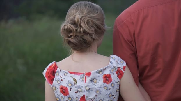 Lovers couple holding hands in a forest. Clip. Rear view of couple walking in forest holding hands.