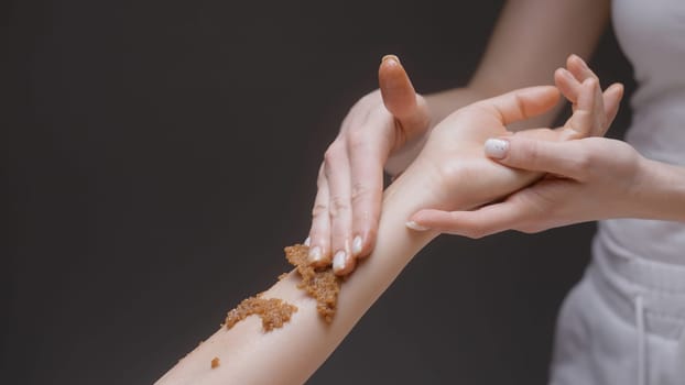 Close-up of masseur rubbing scrub on hand. Action. Gentle movements of masseur on client's hand. Beautiful massage movements and rubbing.