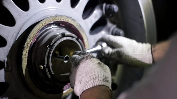 Aircraft brake repair. Close up of airplane wheel and shaft. Huge airplane tyre with shaft and landing gear of plane under airplane. Engineer fixing aircraft's wheel 4K