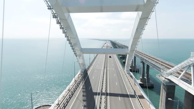 Top view of driving cars on bridge over river. Action. Motorway on bridge over river. Beautiful bridge with highway over blue river.