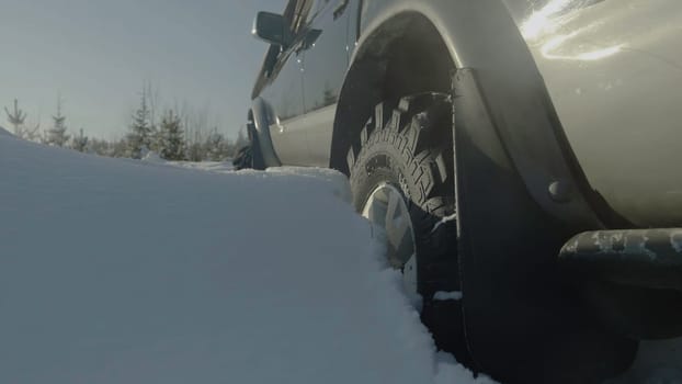 Driving SUV car in winter on forest road with much snow. Car stuck in the woods. Closeup.
