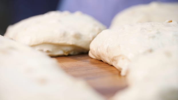 Close up view for raw pieces of pastry lying on the wooden board on the table. Traditional delicious pastry pieces with raisins ready for baking.