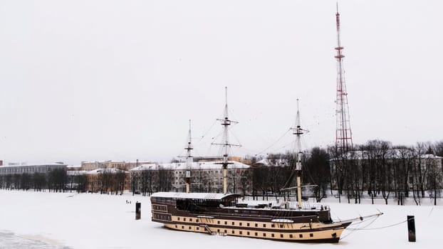 Floating restaurant Frigate Flagship on the Volkhov river on a winter day, Velikiy Novgorod. Concept. Beautiful retro stylized ship on a snow and ice covered river on cloudy sky background
