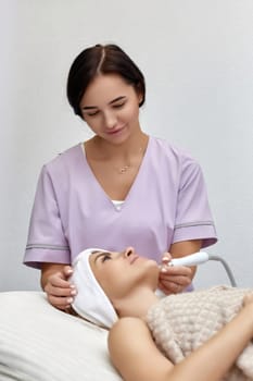 cosmetologist making procedure microdermabrasion on the face in beauty salon