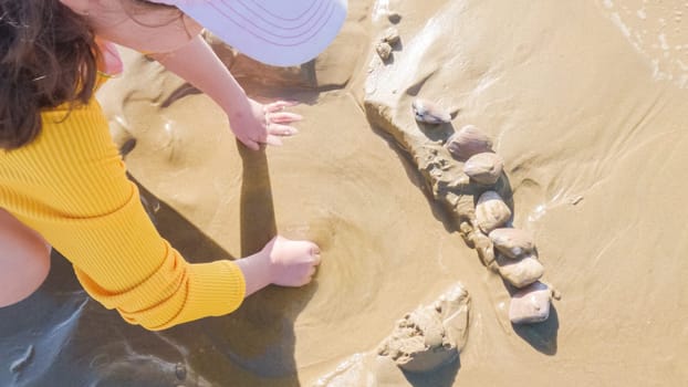 Little girl joyfully clamming on Pismo Beach, bundled up for the winter chill as she explores the sands for seashells and clams.