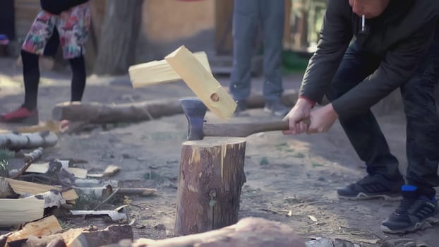 Slowly chopped the stump for firewood with an axe. CLIP. Wood is being chopped in the foreground. A man is chopping firewood on a stump. People watch another person chopping wood.