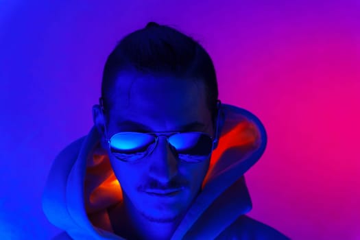 Portrait of a millennial man in neon light. Hipster in a hoodie. Selective focus