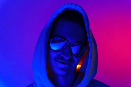 Portrait of a young man in profile at studio. Male model in colorful bright neon lights posing on purple background