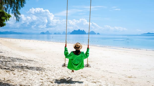 woman on the beach of the tropical Island Naka Island near Phuket Thailand, the woman at a swing on the beach. Naka Island Phuket Thailand