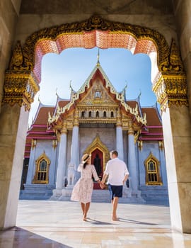 Asian woman with a hat and European men visiting a temple, a couple on a city trip in Bangkok Thailand, Wat Benchamabophit temple in Bangkok Thailand, The Marble temple in Bangkok.