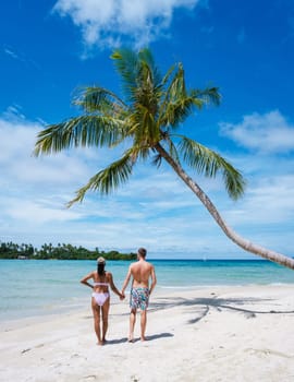 Tropical Island Koh Kood or Koh Kut Thailand. Couple men and women on vacation in Thailand walking at the beach with a hanging palm tree, holiday concept Island hopping in Eastern Thailand Trang