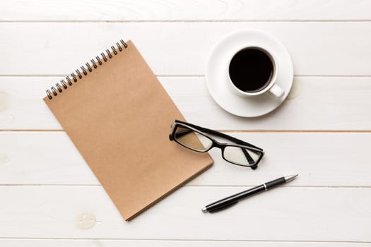 Modern office desk table with notebook and other supplies with cup of coffee. Blank notebook page for you design. Top view, flat lay.