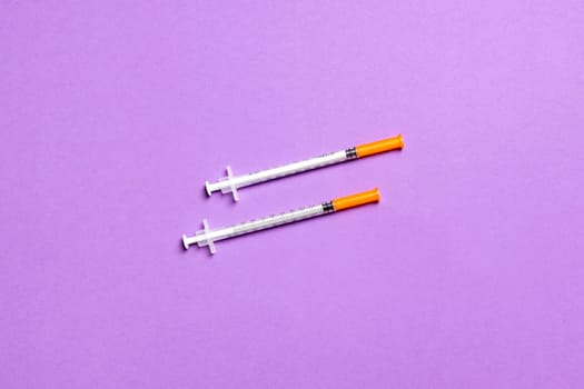 Top view of two insulin syringe at colorful background with copy space. High level of glucose concept.