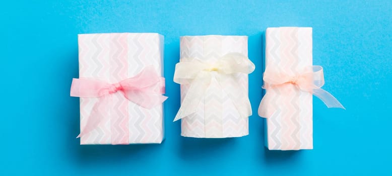 Gift box with Colored bow for Christmas or New Year day on blue background, top view.