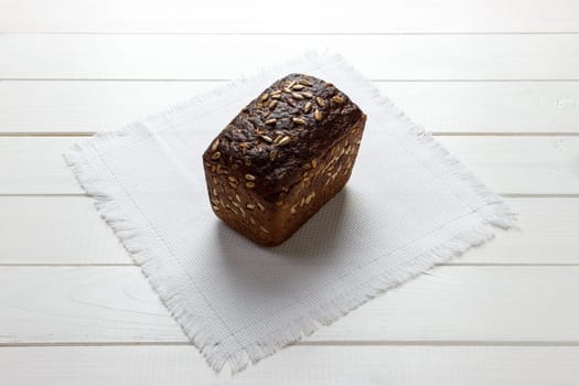 Traditional round rye bread on white fabrick cloth. Bread on wooden background.