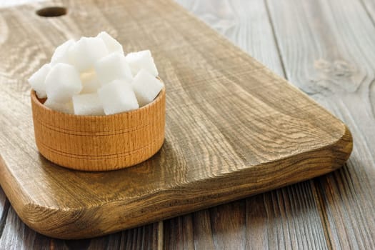 Sugar cubes in bowl on wooden table. White sugar cubes in bowl.