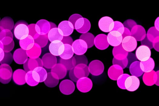 Unfocused abstract purple bokeh on black background. defocused and blurred many round light.