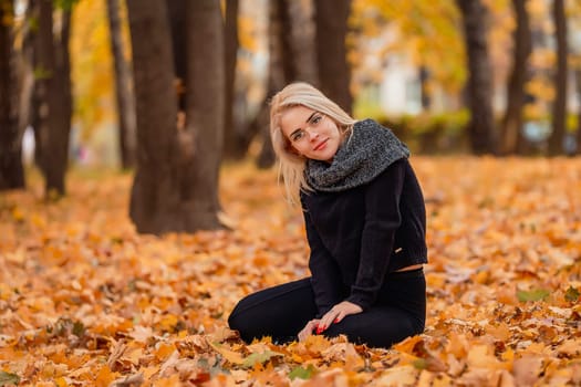 a girl with blond hair and glasses sits in an autumn park