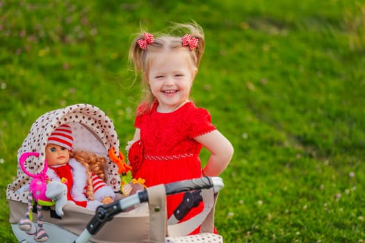 a child with a toy stroller and a doll is playing in nature