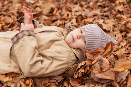 portrait of a little girl lying in fallen autumn leaves