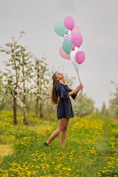 girl with balloons in a field with blooming apple orchards
