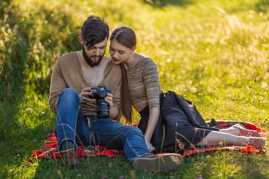 young couple sits in nature and looks at the camera at the resulting picture