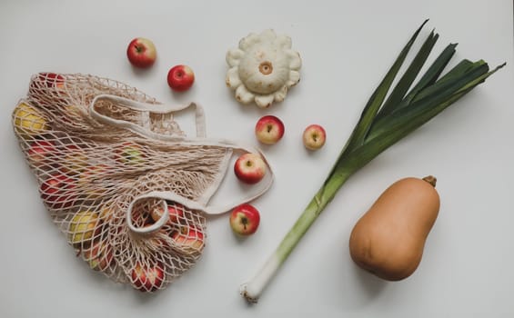 autumn harvest with pumpkin, sqush, apples in a eco mesh shopping bag. zero waste, no plastic