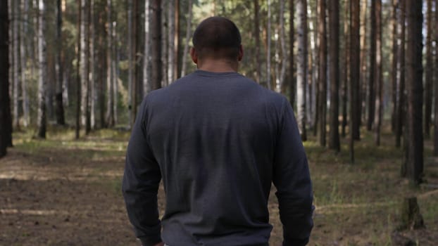 Rear view of fit young man with muscular build standing against sport ground background. Fighter looking at copy space. The muscular male back.