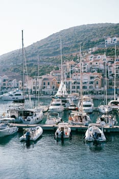Yachts stand in rows along the piers in front of colorful houses. Lustica Bay Marina, Montenegro. High quality photo