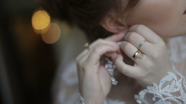 Beautiful bride in puts on earring. Beauty model girl is wearing jewelry for marriage. Wedding female portrait. Woman with curly hair and lace veil. jewelry and beauty concept - close up of beautiful woman wearing shiny diamond earrings HD