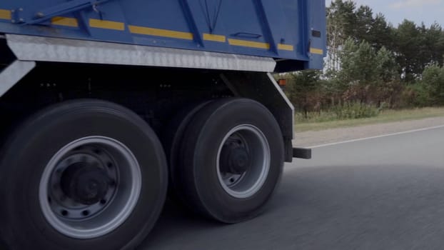 Big truck.Scene.A huge truck with a blue body with a long road and a forest with trees is visible from behind. High quality FullHD footage