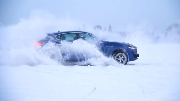 Winter driving. Blue car drives by icy track on snow covered lake at winter. Sport car racing on snow race track in winter. Driving a race car on a snowy road.