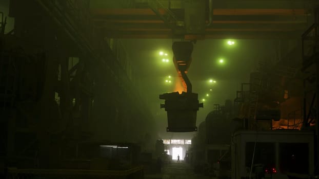 View inside of metallurgical shop with grean glow and big vat with molten steel inside, heavy industry concept. Hot steel vat at the metallurgical plant being transported.