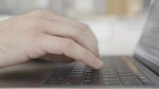 Working at home with laptop, male hands on the keyboard. Close up side view of hands typing on keypad of the computer, concept of modern technologies.