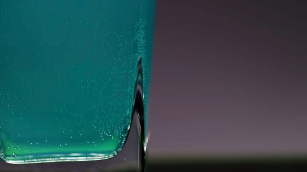 Close up of light blue bubbling beverage on pink lighted wall background. Stock clip. Concept of having fun at the night bar