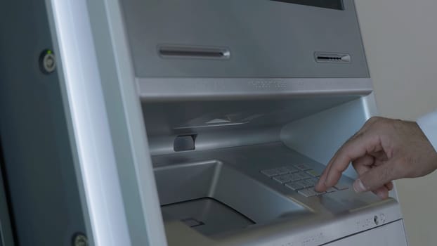 Male hand entering pin code on ATM keyboard, withdrawing money from account. HDR. Automatic machine for cash withdrawal