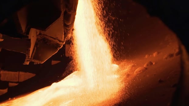 Molten raw materials in furnace. Stock footage. Close-up of bright molten substance pouring out in stream in industrial furnace.