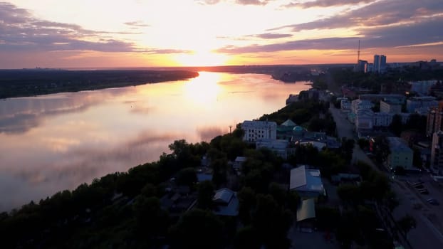 Flying above the city and a temple with golden dome located by the river. Clip. The beauty of small summer town in the evening