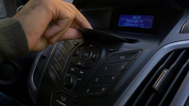 Man's hand puts the disk into the car player. Button control for compact disk player in a car. Hand puts the disk into the radio car HD