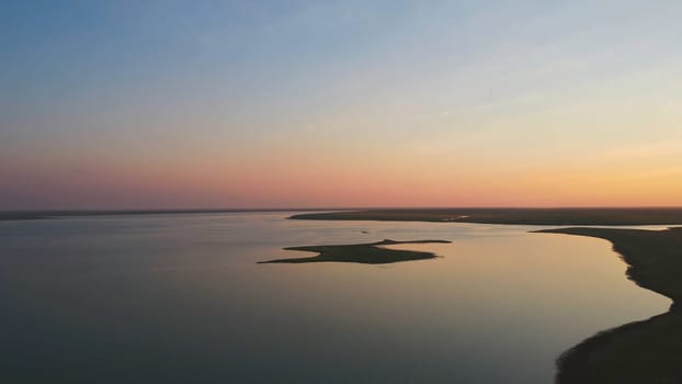 A flock of birds on the background of colorful sky. Sunset on the river. Island of gulls. Birds fly at sunset, aerial.