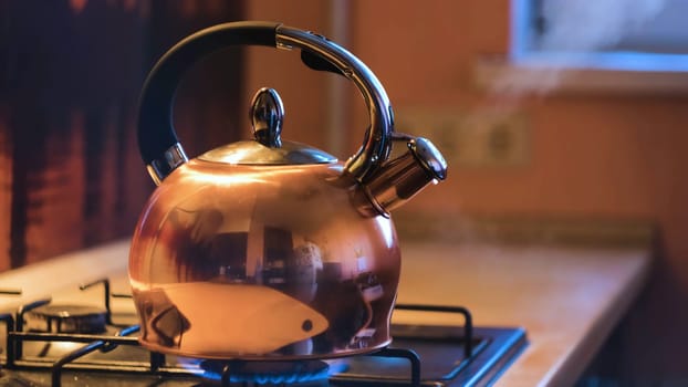 Close-up of silver teapot boiling on stove. Concept. Boiling kettle on stove in beautiful evening kitchen interior. Stream of steam comes out of kettle on stove.